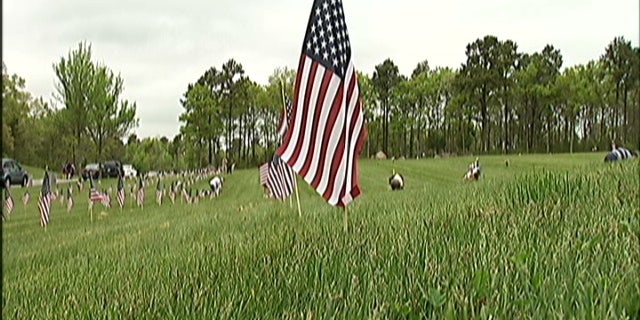 Hundreds of volunteers have traveled to Cape Cod to plant 50,000 flags at a military veteran's cemetery that until now has forbidden flags on the markers.