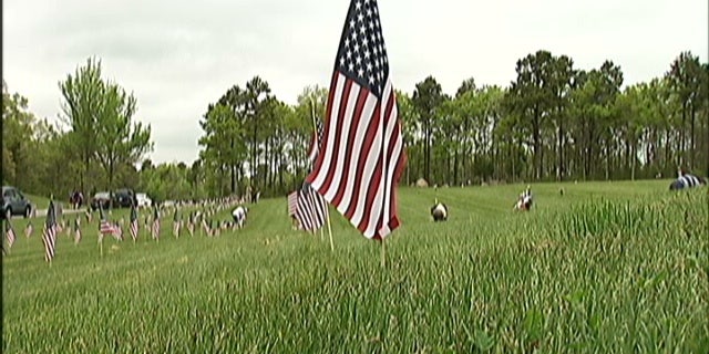 Hundreds of volunteers have traveled to Cape Cod to plant 50,000 flags at a military veteran's cemetery that until now has forbidden flags on the markers.