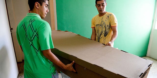 Two young men carry a cardboard coffin in Barquisimeto, Venezuela on August 9, 2016.Due to the high cost and the shortage of materials that make the acquisition of coffins difficult in Venezuela, they are being made in cheap timber planks and even cardboard. (Photo credit FEDERICO PARRA/AFP/Getty Images)