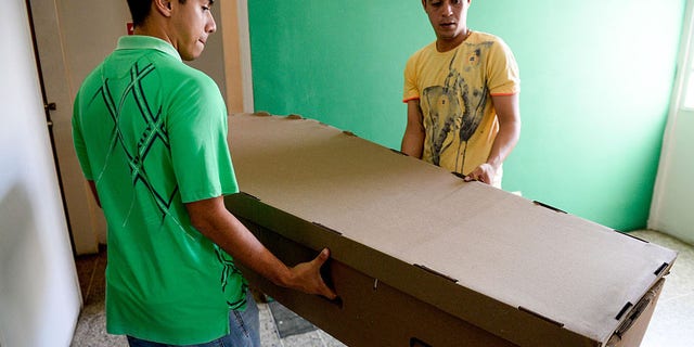 Two young men carry a cardboard coffin in Barquisimeto, Venezuela on August 9, 2016.Due to the high cost and the shortage of materials that make the acquisition of coffins difficult in Venezuela, they are being made in cheap timber planks and even cardboard. (Photo credit FEDERICO PARRA/AFP/Getty Images)