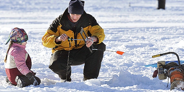 Troy Turner, Milford , Maine, and his daughter Kmoi set to work retrieving their ice fishing traps on a cold but sunny day at Pickerel Pond, Milford, Saturday, January 10, 2009.