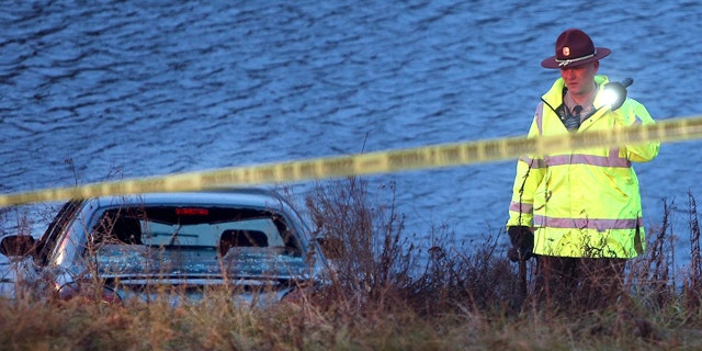 Nov. 21, 2013: A police officer investigates the scene where six people were rescued after their car went into a holding pond near a highway exit ramp.