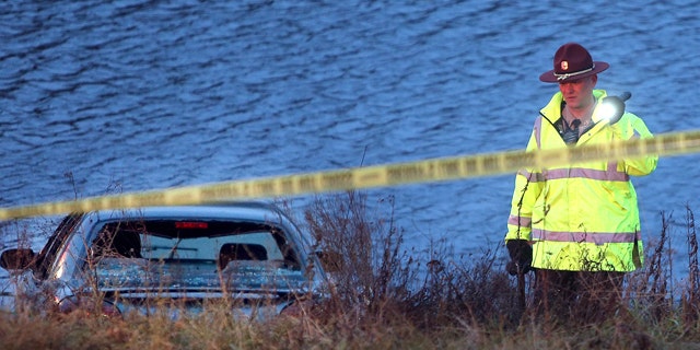Nov. 21, 2013: A police officer investigates the scene where six people were rescued after their car went into a holding pond near a highway exit ramp.