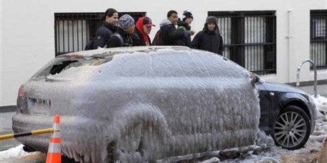 Jan. 24: Pedestrians gawk at Pete Helfer's car, frozen under a sheet of ice on a New York City street after a water pipe broke nearby (AP).
