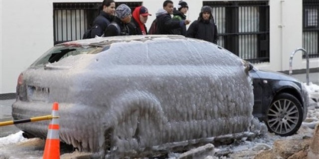 Jan. 24: Pedestrians gawk at Pete Helfer's car, frozen under a sheet of ice on a New York City street after a water pipe broke nearby (AP).