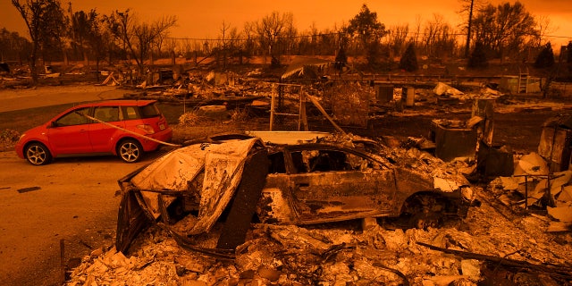 Two vehicles that endured the Carr Fire, one with minor cosmetic damage and one destroyed, rest among leveled homes in the Lake Keswick Estates area of Redding, Calif., on Friday, July 27, 2018.