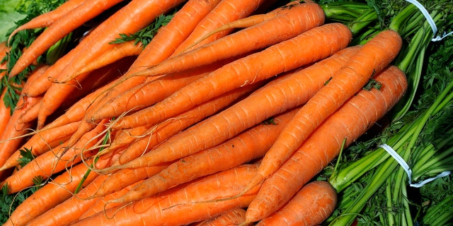 Food street market. Bundles of orange carrots on sale on a stand of fruit and vegetables. Organic farm.