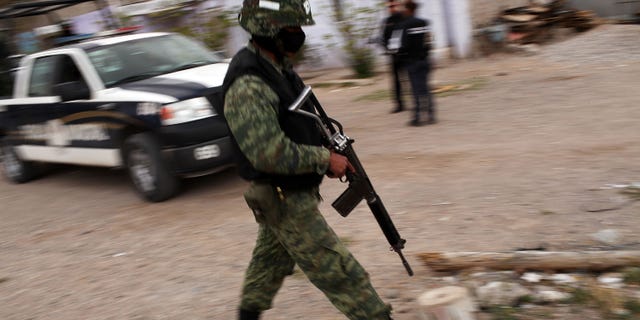 JUAREZ, MEXICO - MARCH 23: Military police stand guard at the scene of a murder on March 23, 2010 in Juarez, Mexico. Secretary of State Hillary Rodham Clinton, Defense Secretary Robert Gates, and Homeland Security Secretary Janet Napolitano all visited Mexico on today for discussions centered on Mexico's endemic drug-related violence. The border city of Juarez, Mexico has been racked by violent drug-related crime recently and has quickly become one of the most dangerous cities in the world in which to live. As drug cartels have been fighting over ever-lucrative drug corridors along the United States border, the murder rate in Juarez has risen to 173 slayings for every 100,000 residents. President Felipe Calderon's strategy of sending 7000 troops to Juarez has not mitigated the situation. With a population of 1.3 million, 2,600 people died in drug-related violence last year and 500 so far this year, including two Americans recently who worked for the U.S. Consulate and were killed as they returned from a child's party. (Photo by Spencer Platt/Getty Images)