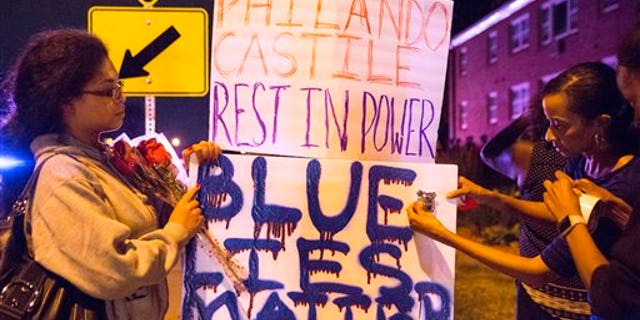 Protester's hang signs on a post near the scene of Philando Castile's shooting in Falcon Heights, Minn., Thursday, July 7, 2016. Castile was shot in a car Wednesday night in the largely middle-class St. Paul suburb of Falcon Heights. Police have said the incident began when an officer initiated a traffic stop in suburban Falcon Heights but have not further explained what led to the shooting. .(Leila Navidi/Star Tribune via AP)