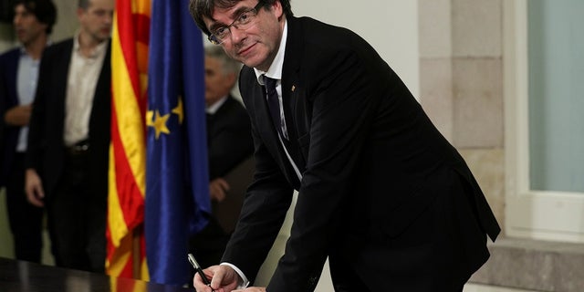 Catalan President Carles Puigdemont signs a declaration of independence at the Catalan regional parliament in Barcelona on Oct. 10.