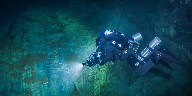 In this underwater photo taken Aug. 15, 2015 in the flooded Hranicka Propast, or Hranice Abyss, in the Czech Republic Polish explorer Slawomir Packo is exploring the limestone abyss and preparing for deeper exploration with the use of a remotely-operated underwater robot, or ROV. (Krzysztof Starnawski of EXPEDITION via AP)