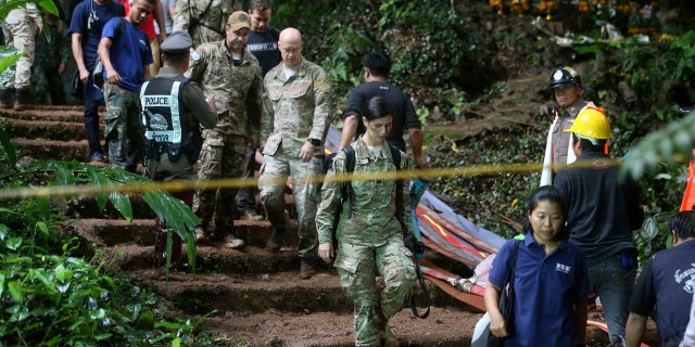 U.S. Special Operations Command Pacific Search and Rescue team personnel walk out of a cave where a young soccer team and their coach are believed to be missing in northern Thailand.