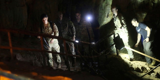 U.S. Special Operations Command Pacific Search and Rescue team personnel walk in a cave where a young soccer team and their coach are believed to be missing.