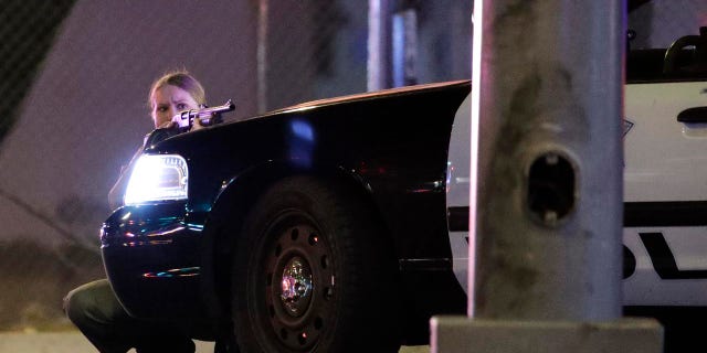 A police officer takes cover behind a police vehicle during a shooting near the Mandalay Bay resort and casino on the Las Vegas Strip, Sunday, Oct. 1, 2017, in Las Vegas. (AP Photo/John Locher)