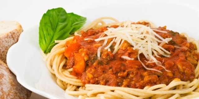 Bowl of whole wheat spaghetti and sauce. The sauce includes ground turkey, fresh basil, tomato sauce, bell peppers, onions, mushrooms, garlic, olive oil and italian seasonings.