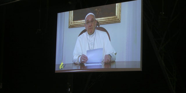 Pope Francis is seen on a giant screen during his video address to a session of 500 experts drafting the so-called Milan Charter that seeks commitments from governments, organizations and individuals during the Expo 2015 world's fair to resolve such issues as food security, decreasing food waste and ensuring biodiversity. in Milan, Italy, Friday, Feb. 7, 2015. Pope Francis emphasized the right to food as fundamental saying the paradox of abundance described by Pope John Paul II -- whereby there is food for everyone yet not everyone can eat -- continues to be an issue.(AP Photo/Antonio Calanni)