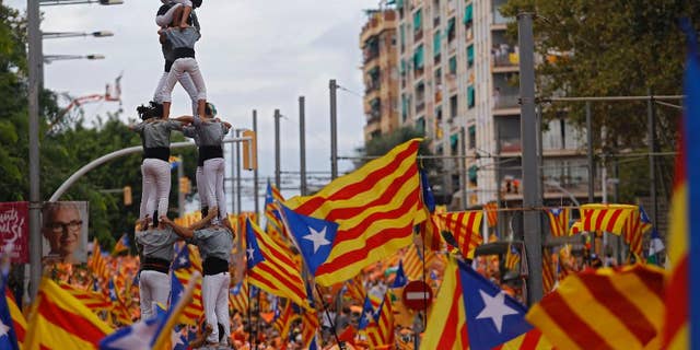 Members of a Castellers complete their human tower as others wave pro-independence Catalan flags, known as the Estelada flag, during a rally calling for the independence of Catalonia, in Barcelona, Spain, Friday, Sept. 11, 2015. Advocates of independence for Spain's northeastern region of Catalonia on Friday launched their campaign to try to elect a majority of secessionists in regional parliamentary elections on Sept. 27. (AP Photo/Francisco Seco)