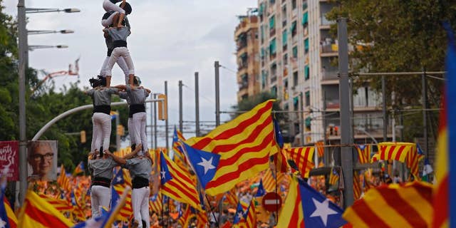 Members of a Castellers complete their human tower as others wave pro-independence Catalan flags, known as the Estelada flag, during a rally calling for the independence of Catalonia, in Barcelona, Spain, Friday, Sept. 11, 2015. Advocates of independence for Spain's northeastern region of Catalonia on Friday launched their campaign to try to elect a majority of secessionists in regional parliamentary elections on Sept. 27. (AP Photo/Francisco Seco)