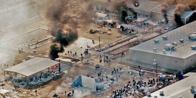 FILE - In this Thursday, Feb. 5, 2009 file photo, plumes of smoke rise from the yard and recreation building of Reeves County Detention Center 1 unit in Pecos, Texas. The fires came five days after inmates set fires to other parts of the RCDC I and II units during a riot blamed on complaints about inadequate health care and food. A Justice Department Inspector General report released Thursday, April 23, 2015, was critical of the operation at the the 2,400-bed facility that primarily houses "low-level" immigrants in the country illegally. (AP Photo/Pecos Enterprise, Smokey Briggs, file)
