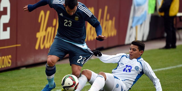 El Salvador's Alexander Larin (13) pulls on the shorts of Carlos Tevez (23) during the first half of an international friendly soccer game Saturday, March 28, 2015, in Landover, Md. (AP Photo/Nick Wass)