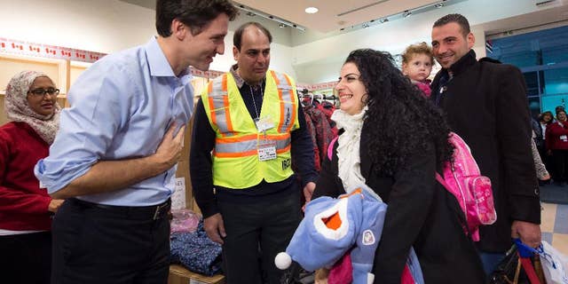 FILE - In this Dec. 11, 2015 file photo, Prime Minister Justin Trudeau, left, greets Georgina Zires, center, Madeleine Jamkossian, second right, and her father Kevork Jamkossian, refugees fleeing from Syria, as they arrive at Pearson International airport, in Toronto. Trudeau has a message for refugees rejected by U.S. President Donald Trump: Canada will take you. He also intends to talk to Trump about the success of Canada’s refugee policy. Trudeau reacted to Trump’s ban of Muslims from certain countries by tweeting Saturday: “To those fleeing persecution, terror & war, Canadians will welcome you, regardless of your faith. Diversity is our strength #WelcomeToCanada.” (Nathan Denette/The Canadian Press via AP, File)