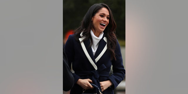 Meghan Markle layered her cozy wrap coat over a white All Saints turtleneck and black cigarette Alexander Wang pants.