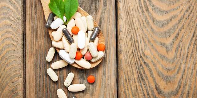 pills on spoon with leaves on a wooden background