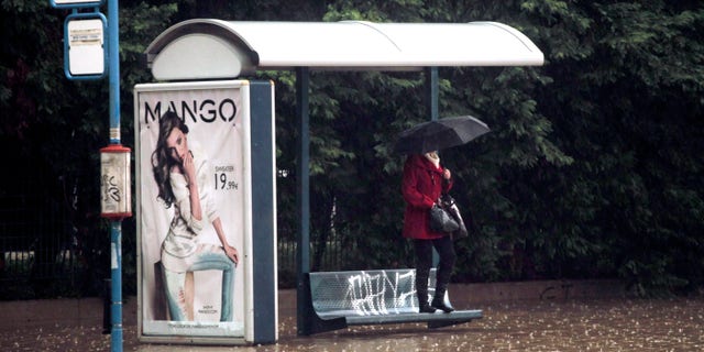 A woman shelters from the rain and the flodding at a bus stop, by standing on a bench, on a flooded highway linking Athens with its port of Piraeus, during a rainstorm on Friday, Feb. 22, 2013. Hours of heavy rainfall in Athens caused extensive flooding, inundating basements and forcing authorities to close major roads and a central subway station. The Greek fire brigade says it received more than 900 calls to pump out water in the greater Athens region Friday. (AP Photo/Petros Giannakouris)
