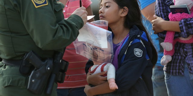 MISSION, TX - JULY 24: Salvadorian immigrant Stefany Marjorie, 8, watches as a U.S. Border Patrol agent records family information on July 24, 2014 in Mission, Texas. Like most of the recent surge of Central American immigrant women and children, her family brought documents, often birth certificates, to prove their nationality to U.S. Border officials. Tens of thousands of immigrant families and unaccompanied minors from Central America have crossed illegally into the United States this year and presented themselves to federal agents, causing a humanitarian crisis on the U.S.-Mexico border. Texas' Rio Grande Valley has become the epicenter of the latest immigrant crisis, as more of them enter illegally from Mexico into that sector than any other stretch of the America's 1,933 mile border with Mexico. (Photo by John Moore/Getty Images)