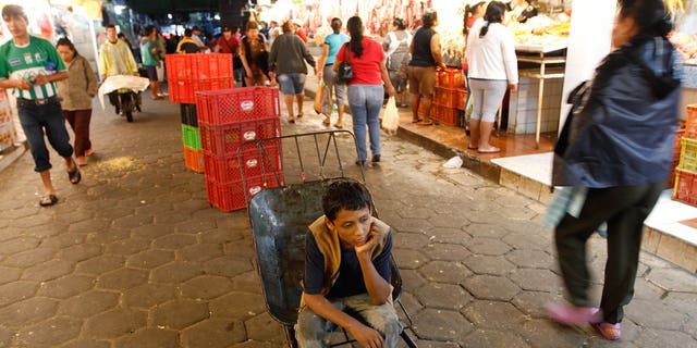A 12-year-old boy rests as he works as a porter at the El Abasto market in Santa Cruz, Bolivia.