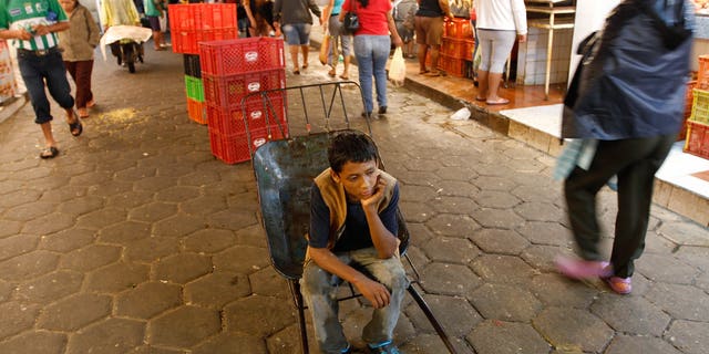 A 12-year-old boy rests as he works as a porter at the El Abasto market in Santa Cruz, Bolivia.