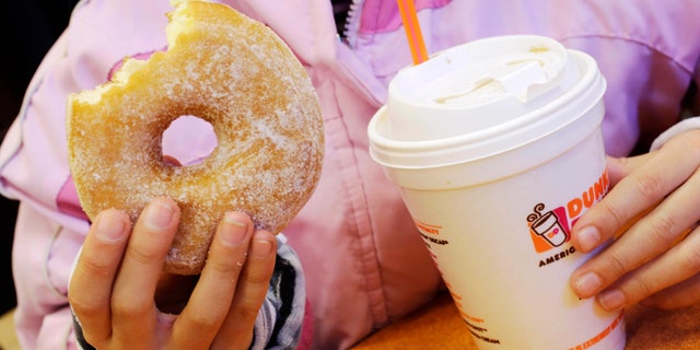 FILE - In this Feb. 14, 2013 file photo, a girl holds a beverage, served in a foam cup, and a donut at a Dunkin' Donuts in New York. The New York City Council's sanitation committee has a hearing set for Monday, Nov. 25, 2013, on proposals to ban plastic-foam food containers or explore recycling them. (AP Photo/Mark Lennihan, File)