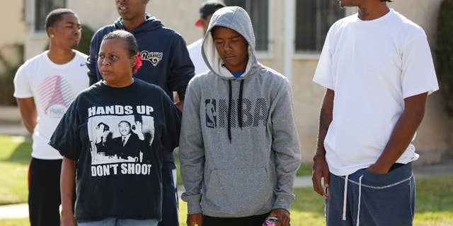Neighbors and members of the community gather around a makeshift memorial to Carnell Snell Jr. on Sunday.