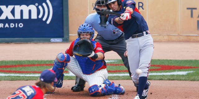 World's Jose Peraza, right, singles during the first inning of the All-Star Futures baseball game in front of United States' catcher Kevin Plawecki, Sunday, July 13, 2014, in Minneapolis. (AP Photo/Paul Sancya)