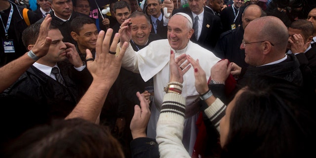 July 25, 2013: People greet Pope Francis, center, as he visits the Varginha slum in Rio de Janeiro, Brazil.