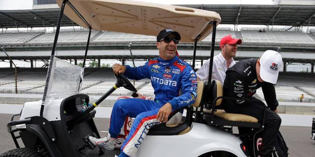 Tony Kanaan, of Brazil, laughs as Sage Karam looks at a flat tire on the cart  they where riding in before the start of practice for the Indianapolis 500 auto race at Indianapolis Motor Speedway in Indianapolis, Monday, May 18, 2015.  (AP Photo/Michael Conroy)