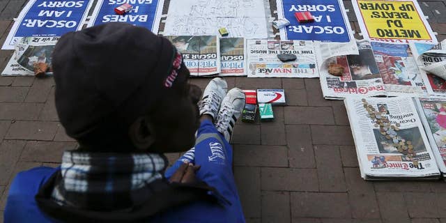 A vendor sells newspaper with headlines on Oscar Pistorius ouside the high court in Pretoria, South Africa, Tuesday, April 8, 2014. Pistorius, who is charged with murder for the shooting death of his girlfriend, Reeva Steenkamp, on Valentines Day in 2013, was testifying for a second day at his murder trial Tuesday, answering questions from his defense lawyer. (AP Photo/Themba Hadebe)