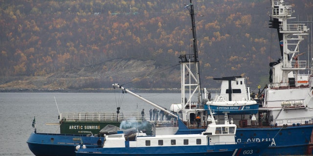 In this photo provided by Greenpeace and taken Wednesday, Oct. 2, 2013, members of the Russian Investigative Committee accompanied by Peter Willcox, the U.S. captain of the Greenpeace ship Arctic Sunrise inspect the vessel, in back, near Murmansk, Russia. Russian investigators have charged the entire 30-member crew of a Greenpeace ship with piracy for a protest at a Russian oil platform in the Arctic. (AP Photo/Greenpeace, Dmitri Sharomov)