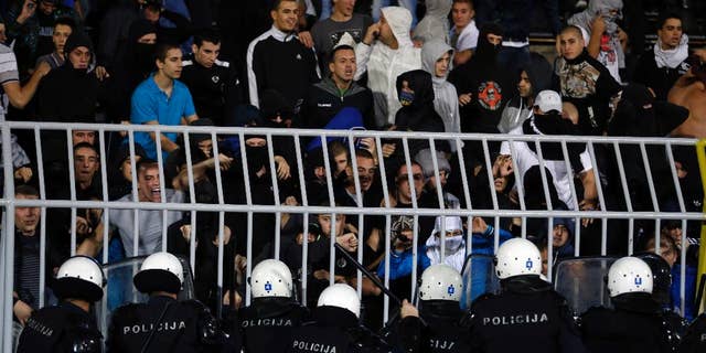Serbian riot police officers clash with Serbian national team supporters during the Euro 2016 Group I qualifying match between Serbia and Albania at the Partizan stadium in Belgrade, Serbia, Tuesday, Oct. 14, 2014. The 2016 European Championship qualifier between Serbia and Albania was abandoned on Tuesday after skirmishes broke out on the pitch involving players and fans over an Albanian flag that was flown above the stadium by a drone. (AP Photo/Marko Drobnjakovic)
