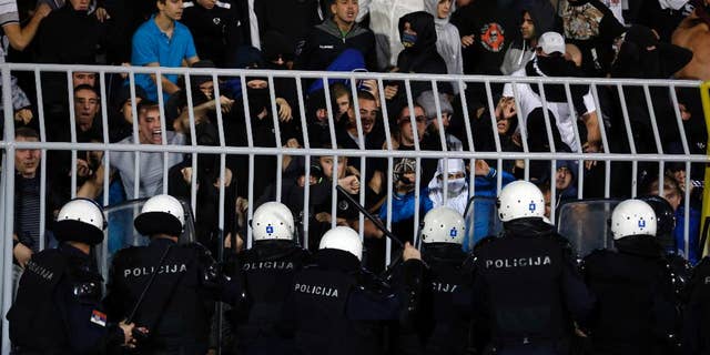 Serbian riot police officers clash with Serbian national team supporters during the Euro 2016 Group I qualifying match between Serbia and Albania at the Partizan stadium in Belgrade, Serbia, Tuesday, Oct. 14, 2014. The 2016 European Championship qualifier between Serbia and Albania was abandoned on Tuesday after skirmishes broke out on the pitch involving players and fans over an Albanian flag that was flown above the stadium by a drone. (AP Photo/Marko Drobnjakovic)