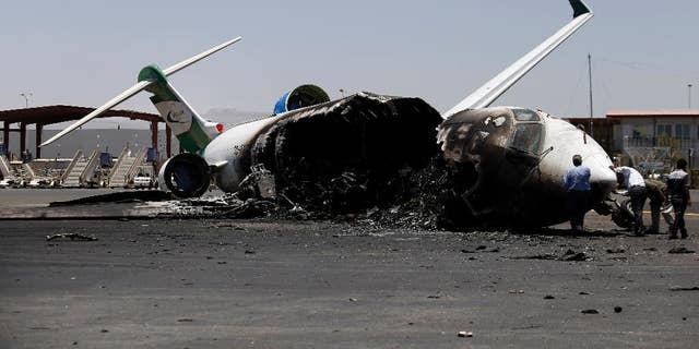 Officials of Felix Airways, a domestic airline, inspect a plane destroyed by Saudi-led airstrikes, at the Sanaa International airport, in Yemen, Wednesday, April 29, 2015. Saudi-led coalition warplanes pounded Shiite rebels and their allies overnight and throughout the day on Tuesday in the Yemeni capital. Around midday, airstrikes hit Sanaa International airport, setting a plane owned by a private company on fire, according to a statement released by the Shiite rebels, known as Houthis. (AP Photo/Hani Mohammed)