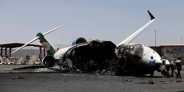Officials of Felix Airways, a domestic airline, inspect a plane destroyed by Saudi-led airstrikes, at the Sanaa International airport, in Yemen, Wednesday, April 29, 2015. Saudi-led coalition warplanes pounded Shiite rebels and their allies overnight and throughout the day on Tuesday in the Yemeni capital. Around midday, airstrikes hit Sanaa International airport, setting a plane owned by a private company on fire, according to a statement released by the Shiite rebels, known as Houthis. (AP Photo/Hani Mohammed)