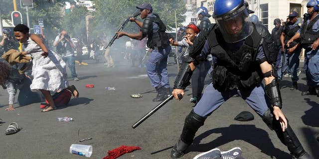 FILE -- In this Wednesday, Sept. 21, 2016 file photo, students run for cover as police fire stun grenades and rubber bullets to disperse them, during a protest for free education at the University of the Witwatersrand in Johannesburg, South Africa. The government on Tuesday, Sept. 27, 2016 called for an investigation, saying protesters were responsible for the death last week at the University of the Witwatersrand in Johannesburg, which has suspended classes because of demonstrations for free education. (AP Photo/Themba Hadebe, File)