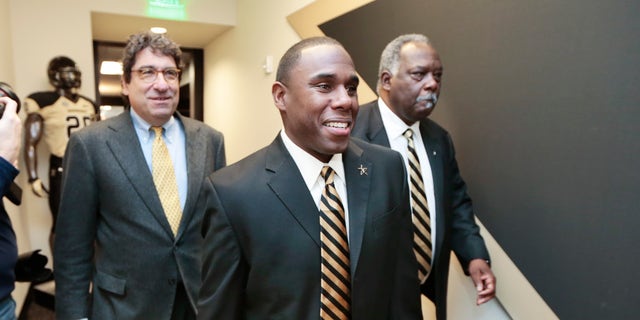Derek Mason, center, walks to a news conference with Chancellor Nicholas S. Zeppos, left, and athletic director David Williams, right, where Mason is to be introduced as the new Vanderbilt football coach Saturday, Jan. 18, 2014, in Nashville, Tenn. Mason was previously the defensive coordinator at Stanford. (AP Photo/Mark Humphrey)