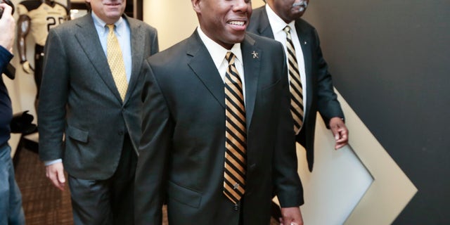 Derek Mason, center, walks to a news conference with Chancellor Nicholas S. Zeppos, left, and athletic director David Williams, right, where Mason is to be introduced as the new Vanderbilt football coach Saturday, Jan. 18, 2014, in Nashville, Tenn. Mason was previously the defensive coordinator at Stanford. (AP Photo/Mark Humphrey)