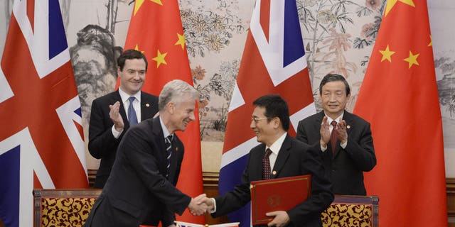 Britain's Chancellor of the Exchequer George Osborne, left, and Chinese Vice premier Ma Kai applaud as their officials shake hands after exchanging signed documents of their agreement during a signing ceremony at the Diaoyutai Guesthouse in Beijing Tuesday, Oct. 15, 2013. (AP Photo/Kota Endo, Pool)