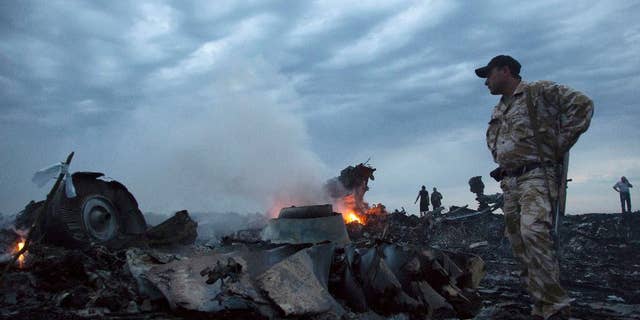 People walk amongst the debris at the crash site of a passenger plane near the village of Grabovo, Ukraine.