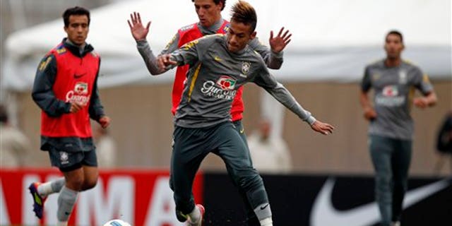 July 15: Brazil's Elano and Neymar, fight for the ball during a training session near Campana, Argentina.