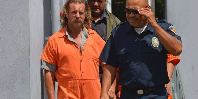 In this Oct. 4, 2016 photo provided by the Samoa News, Dean Fletcher, left, is escorted by a police officer after his initial appearance in the District Court of American Samoa in Pago Pago, American Samoa.