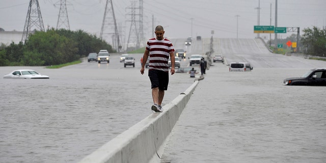 A stranded motorist escapes floodwaters on Interstate 225 after Hurricane Harvey inundated the Texas Gulf coast with rain causing mass flooding, in Houston, Texas, U.S. August 27, 2017. REUTERS/Nick Oxford TPX IMAGES OF THE DAY - RTX3DJQ9